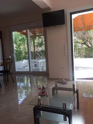 a living room with a glass table and sliding glass doors at The Endless Blue Maisonette in Palaiochóra