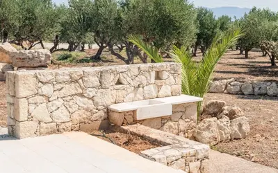 a stone bench next to a stone wall with trees at Xirouchakis farm in Kissamos