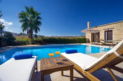 a pool with two chairs and a table with wine glasses at Cozy Stone Villa in Plátanos