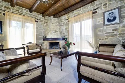 a living room with a stone wall and a fireplace at Cozy Stone Villa in Plátanos