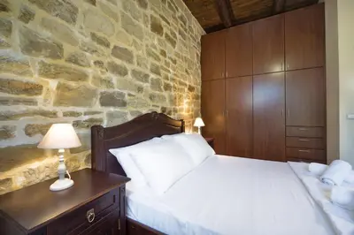 a bedroom with a bed and a stone wall at Cozy Stone Villa in Plátanos