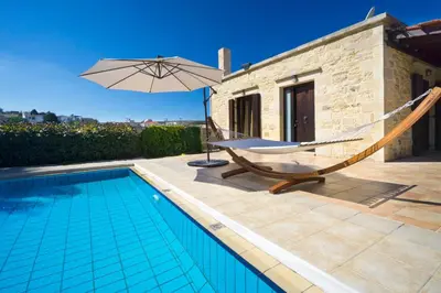 a hammock and an umbrella next to a swimming pool at Cozy Stone Villa in Plátanos