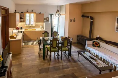 a living room with a table and chairs and a kitchen at Villa Roxani in Mesklá