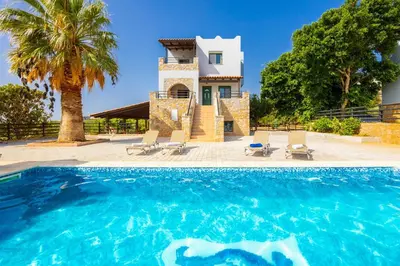 a villa with a swimming pool in front of a house at Theo Beach Villa in Frangokastello