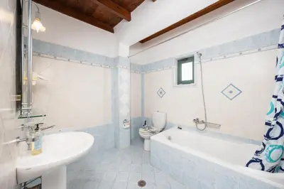 a bathroom with a tub and a toilet and a sink at Theo Beach Villa in Frangokastello
