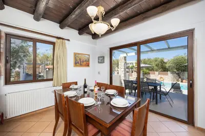a dining room with a table and chairs and a large window at Villa Tzina in Plataniás