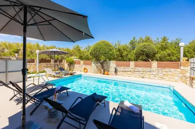 a swimming pool with blue chairs and an umbrella at Villa Tzina in Plataniás