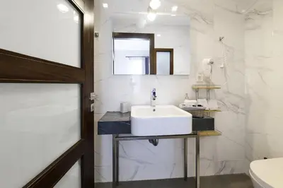 a white bathroom with a sink and a mirror at Nival Luxury Suites in Chania Town