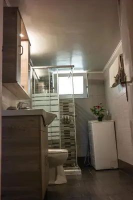 a bathroom with a toilet and a shower with a window at Alexandra Apartment Near Chania Center in Chania Town