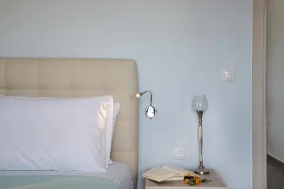 a bedroom with a bed and a lamp and a book at Niovi Seaside Suites in Kissamos