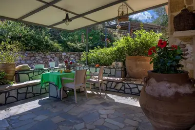 a patio with a green table and chairs and flowers at The Olive House in Kondomari