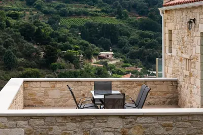 a patio with a table and chairs on a stone wall at Villa Piedra in Manoliópoulon
