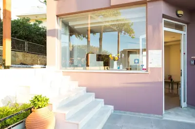 a pink building with stairs and a window at Yasmine Apartments and Rooms in Kato Daratso