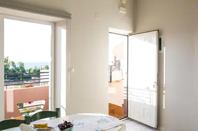 a room with a table and a view of a balcony at Yasmine Apartments and Rooms in Kato Daratso