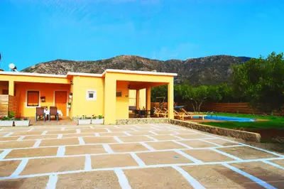 a yellow house with a patio and mountains in the background at White Lake Holiday House in Elafonisi