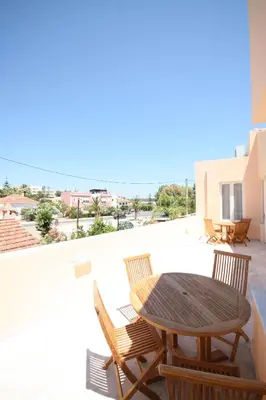 a patio with a wooden table and chairs on a balcony at Elma's Dream Apartments & Villas in Kato Daratso