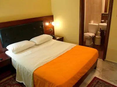 a bedroom with a large bed with an orange blanket at Hotel Filoxenia in Chania Town