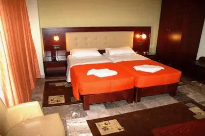 a bedroom with a large orange bed with two towels on it at Hotel Filoxenia in Chania Town