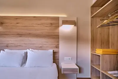 a bedroom with a white bed with a wooden headboard at Emmanouela's Apts in Kissamos