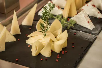 a bunch of cheese on a black cutting board at Spilia Village Hotel & Villas in Spiliá