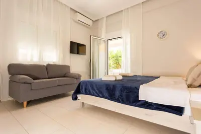 a bedroom with a bed and a chair and a window at Eleni Apartments in Chania Town