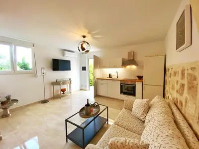 a living room with a couch and a kitchen at MG Cozy Garden View Studio in Korakiaí