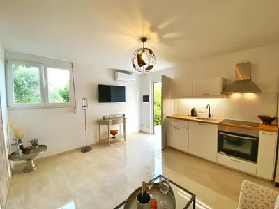 a kitchen with white cabinets and a table in it at MG Cozy Garden View Studio in Korakiaí