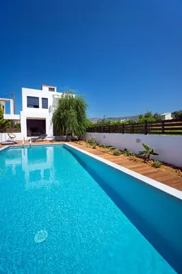 a blue swimming pool in front of a house at Seametry Villa in Chania Town