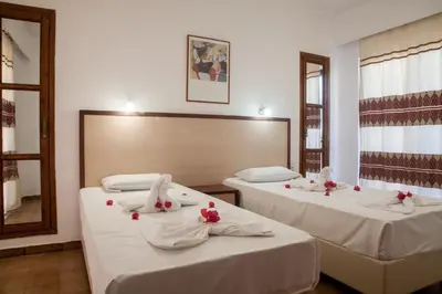 two beds in a room with white sheets and red flowers on them at Ekavi Apartments in Agia Marina Nea Kydonias