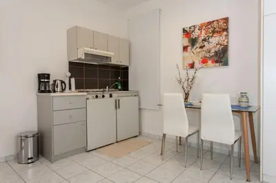 a kitchen with white cabinets and a table and white chairs at Halepa Studios in Chania Town