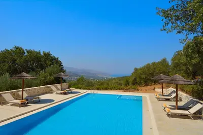 a large swimming pool with chairs and umbrellas at Elia Hotel & Spa in Áno Voúvai