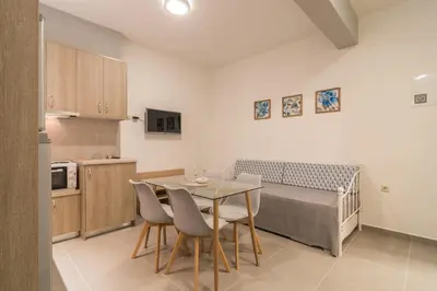 a kitchen with a table and chairs and a bed at AnDi's Apartment's Paleochora in Palaiochóra