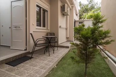 a patio with a table and a chair in front of a door at AnDi's Apartment's Paleochora in Palaiochóra