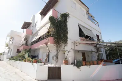 a white building with potted plants on the side of it at Niki Rooms in Palaiochóra