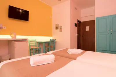 a bedroom with two beds and a table with chairs at Niki Rooms in Palaiochóra