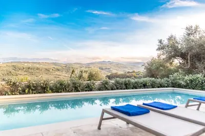 a pool with two lounge chairs and a view of the mountains at Apithano Heated pool on demand in Spiliá