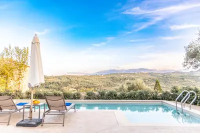 a pool with two chairs and an umbrella and a table with at Apithano Heated pool on demand in Spiliá