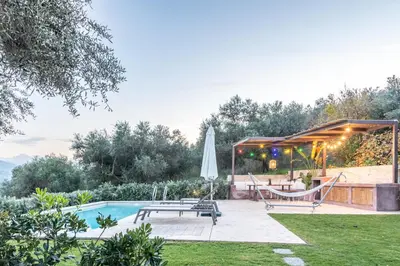 a backyard with a pool and a hammock and an umbrella at Apithano Heated pool on demand in Spiliá