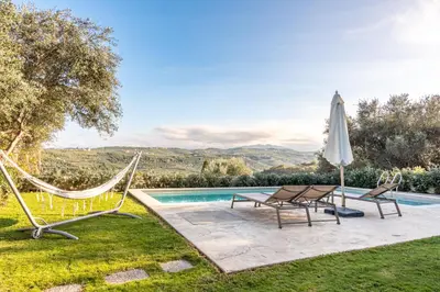 a pool with two chairs and a hammock and an umbrella at Apithano Heated pool on demand in Spiliá