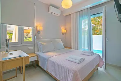 a bedroom with a bed and a desk and a window at Sonja Beachfront Apartments in Kato Daratso