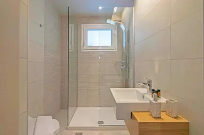 a bathroom with a sink and a glass shower at Sonja Beachfront Apartments in Kato Daratso