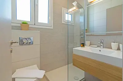 a bathroom with a sink and a glass shower at Sonja Beachfront Apartments in Kato Daratso