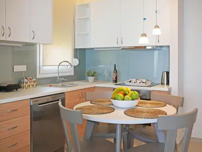 a kitchen with a table with a bowl of fruit on it at Sonja Beachfront Apartments in Kato Daratso