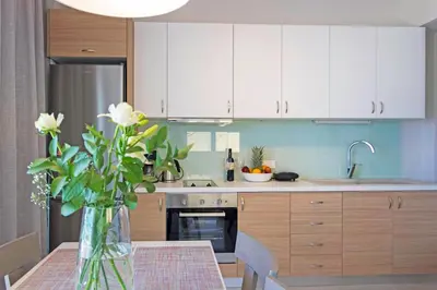 a kitchen with white cabinets and a table with a vase of flowers at Sonja Beachfront Apartments in Kato Daratso