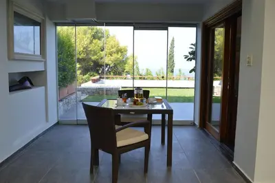 a dining room with a table and chairs and windows at VILLA TERRA CRETA Luxury Retreat and Spa in Chania Town