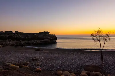 a sunset on a rocky beach with the ocean at Villas Paleochora in Palaiochóra