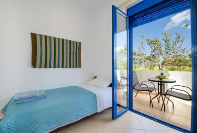 a bedroom with a bed and a balcony with a table at Oasea in Tavronitis