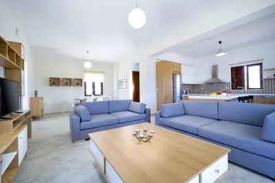 a living room with two blue couches and a table at Seaside Villa Balos in Kissamos