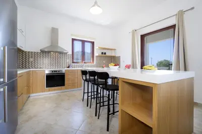 a kitchen with a large white counter and black chairs at Seaside Villa Balos in Kissamos