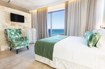 a bedroom with a bed and a window with the ocean at Kalamaki Luxury Suites in Kalamaki Chanion